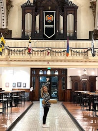 a woman standing in front of an ornate building with a pipe organ